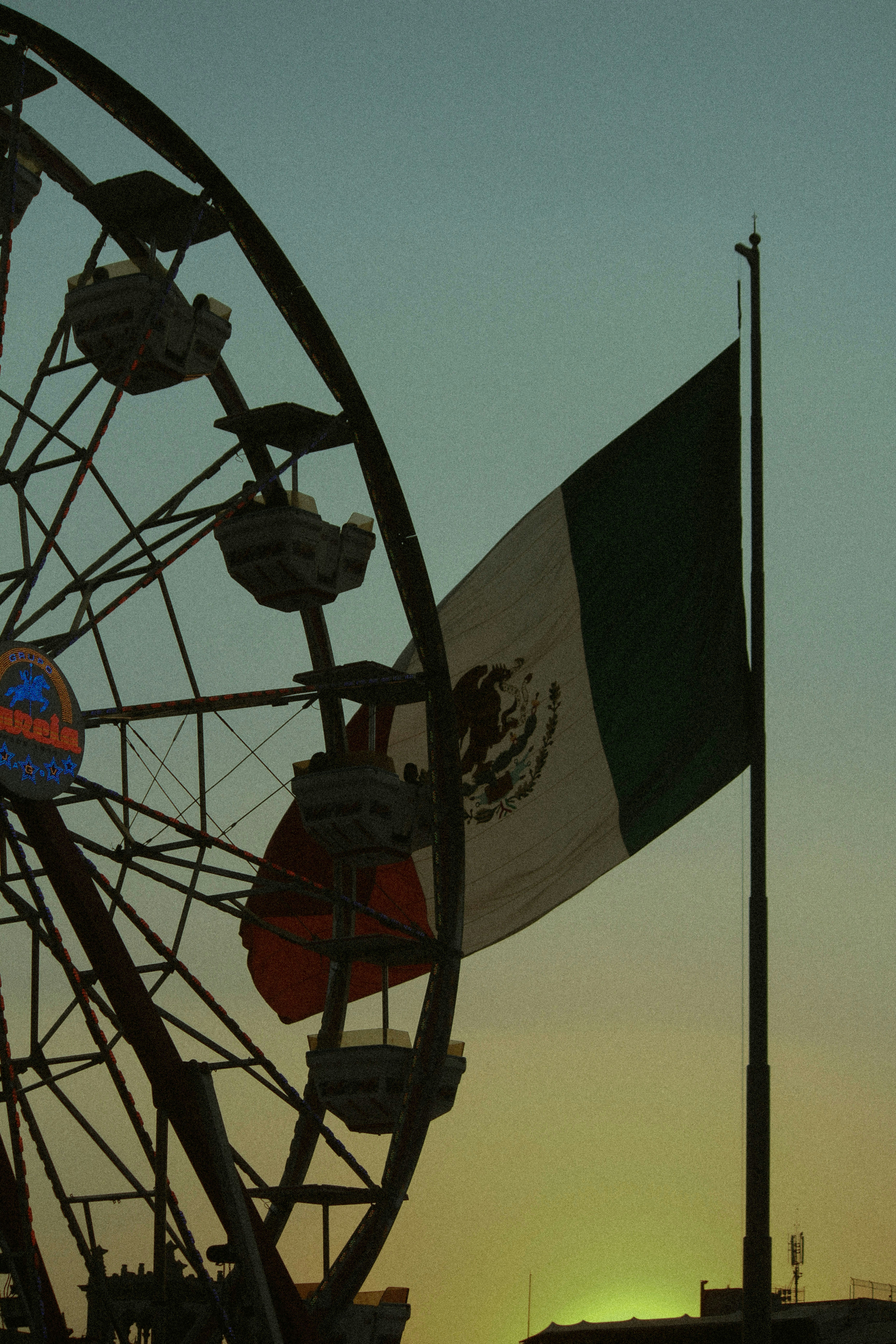a large ferris wheel sitting next to a flag