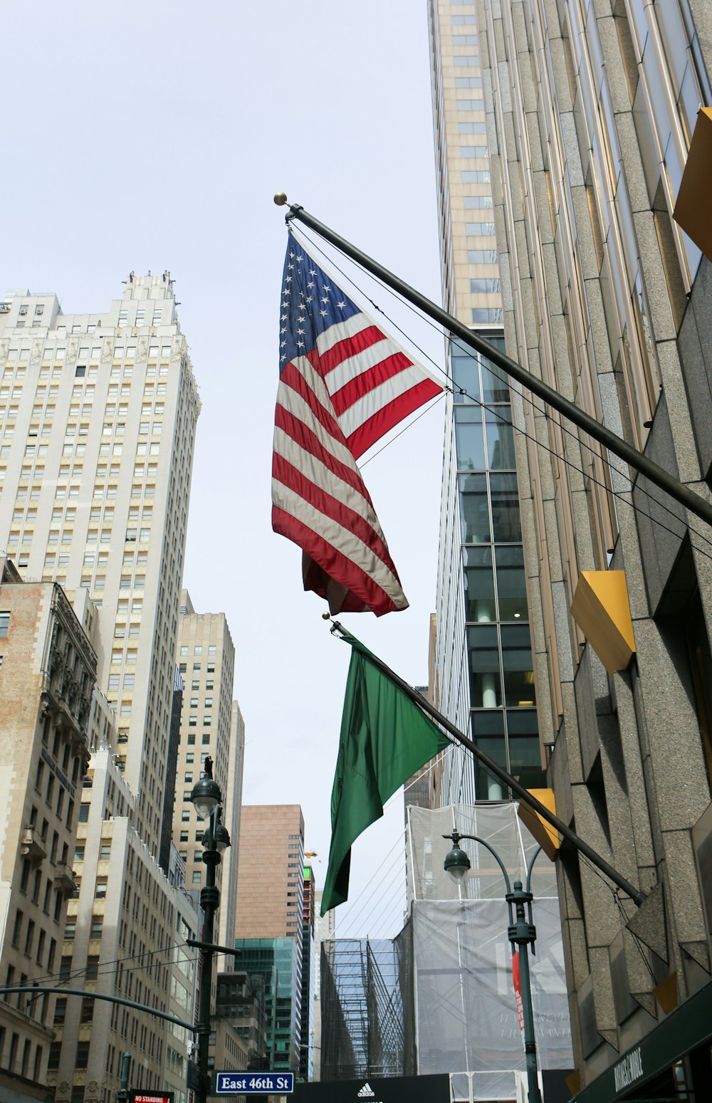 an american and green flag on a pole in a city