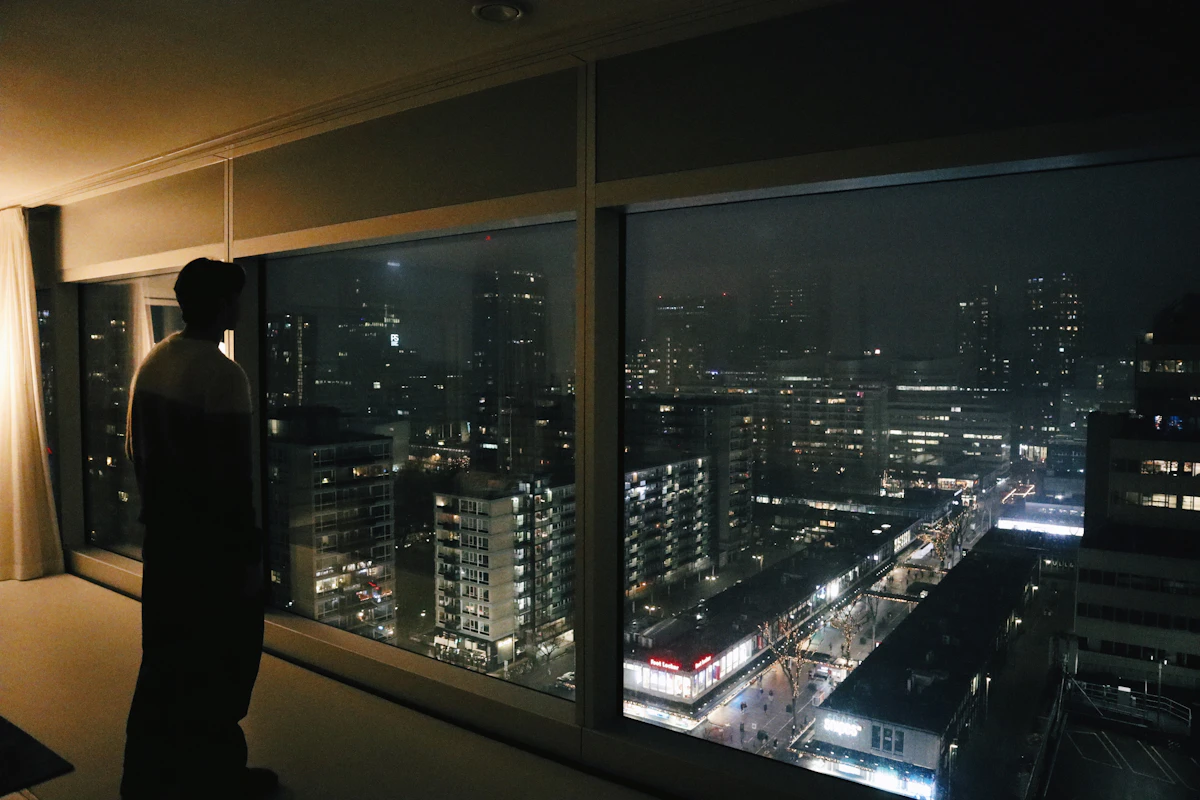 Solo man at window at night — mental clarity