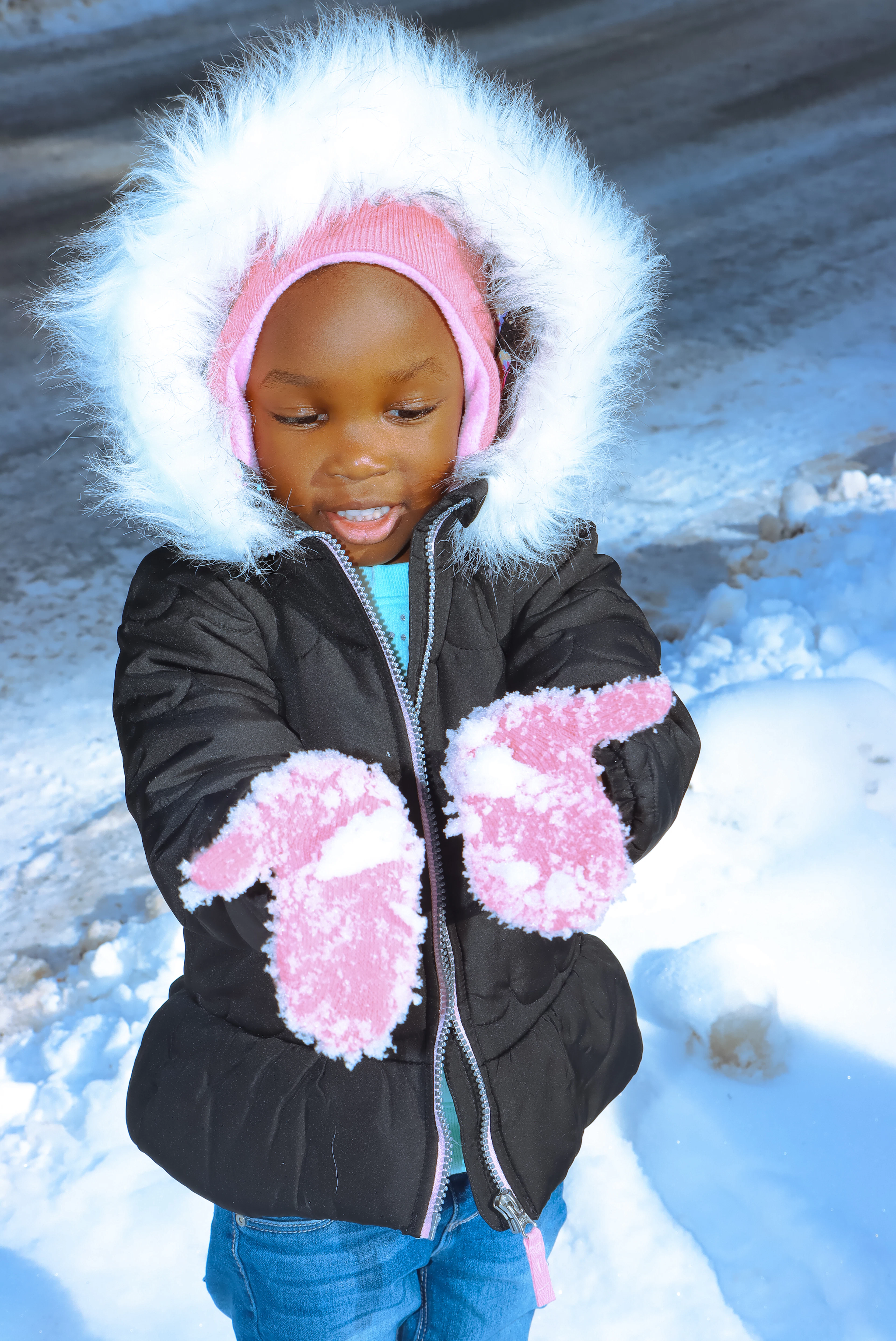 A small child in a winter coat and pink mittens