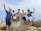 A group of trekkers smiling together at a scenic mountain viewpoint.
