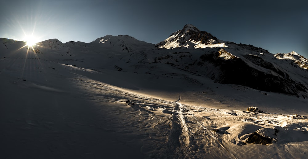 the sun shines brightly on a snowy mountain