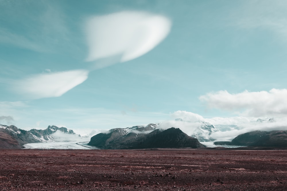 a mountain range with a heart shaped cloud in the sky