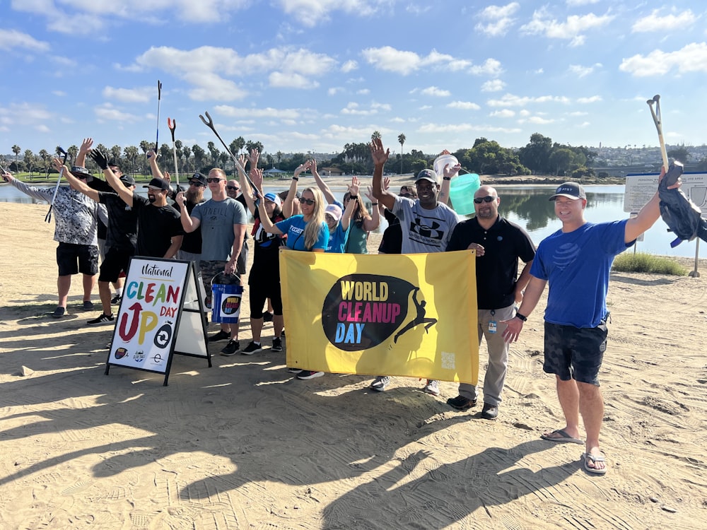 a group of people holding up a sign on the beach