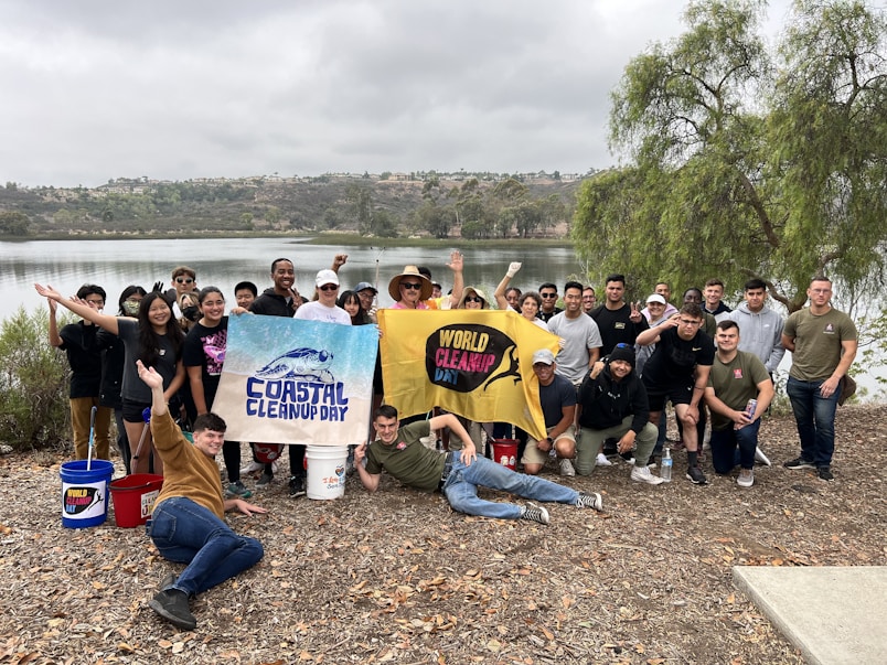 A group photo of diverse volunteers smiling after a successful beach cleanup.