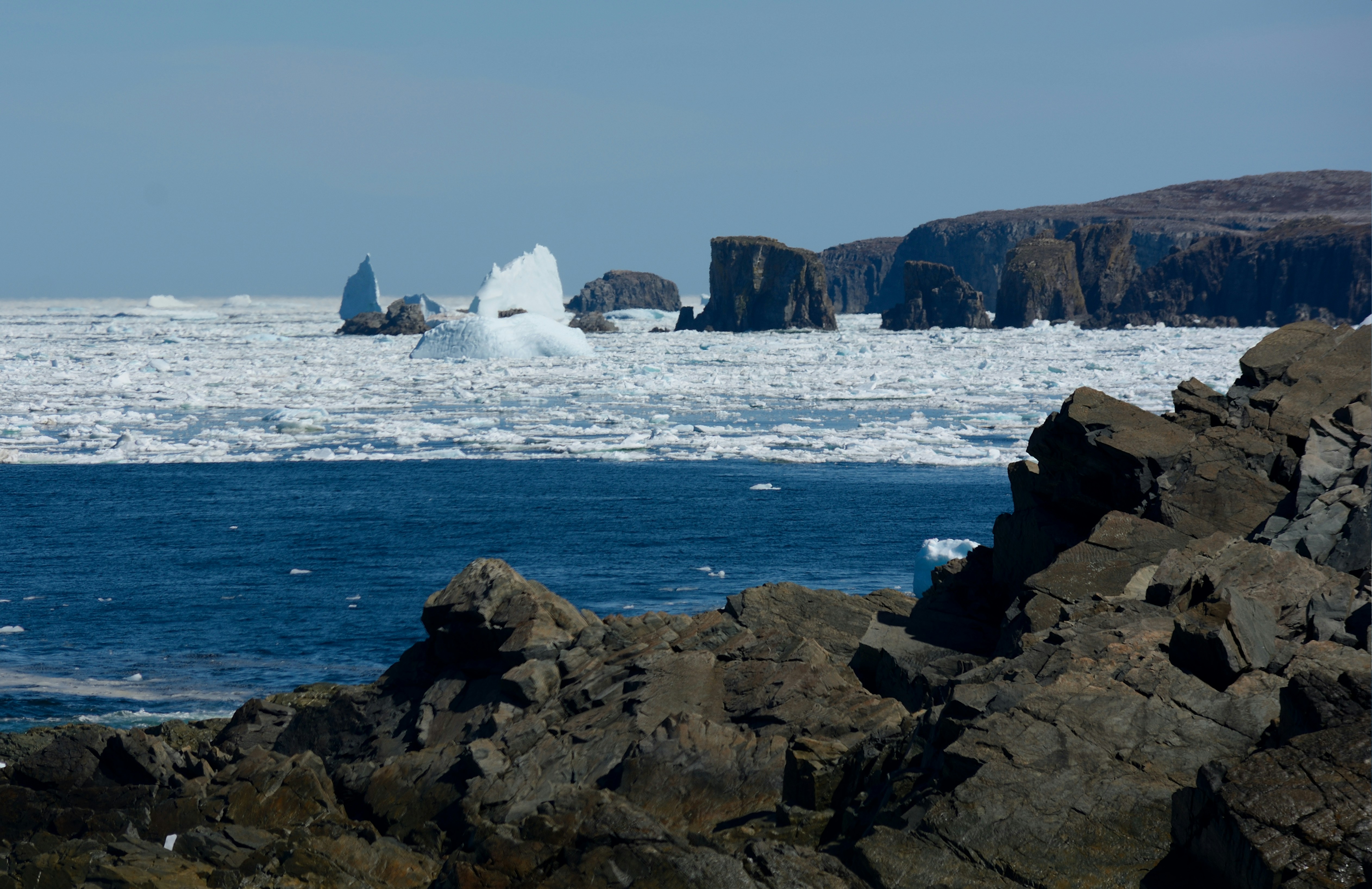 a large iceberg floating in the ocean next to a rocky shore, 