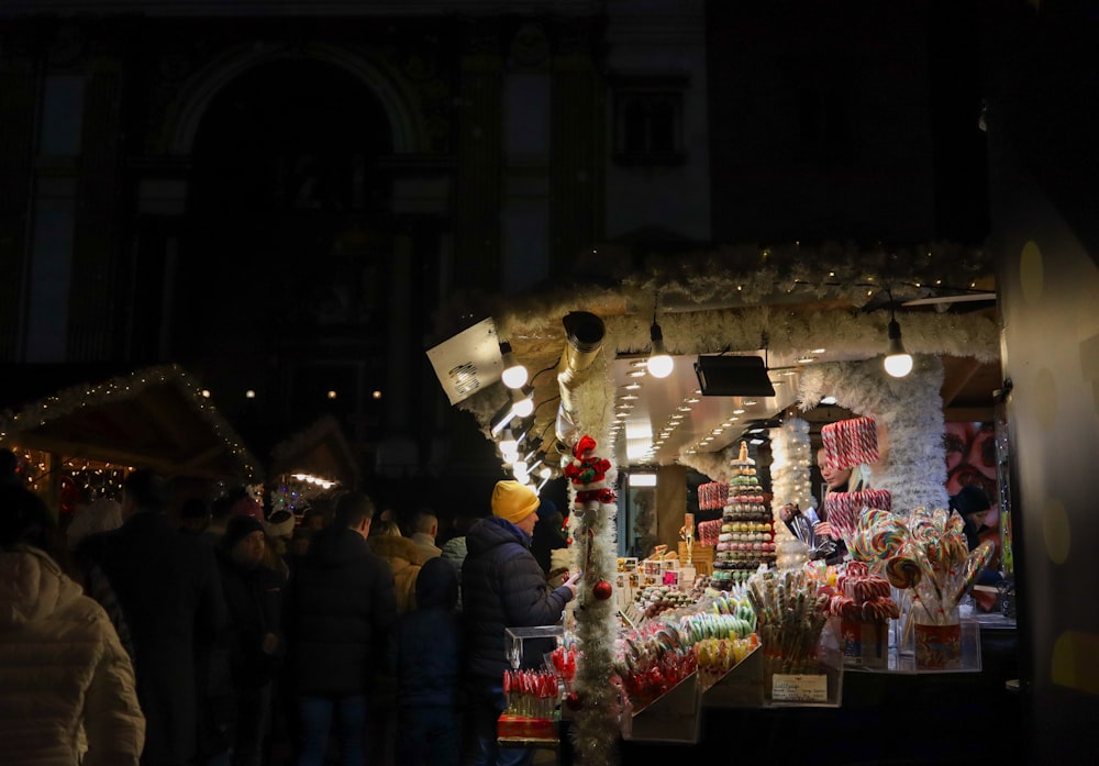 a group of people standing outside of a store at night