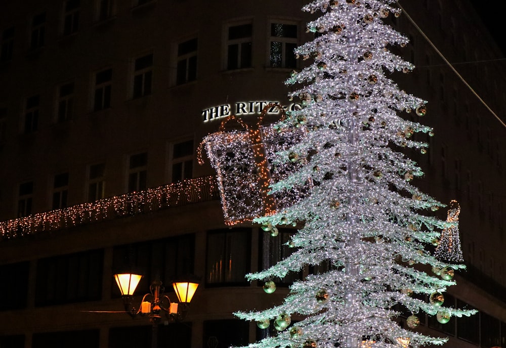 a lit christmas tree in front of a building