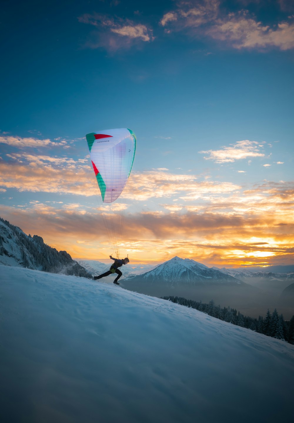 雪に覆われた丘の上で凧を飛ばす人