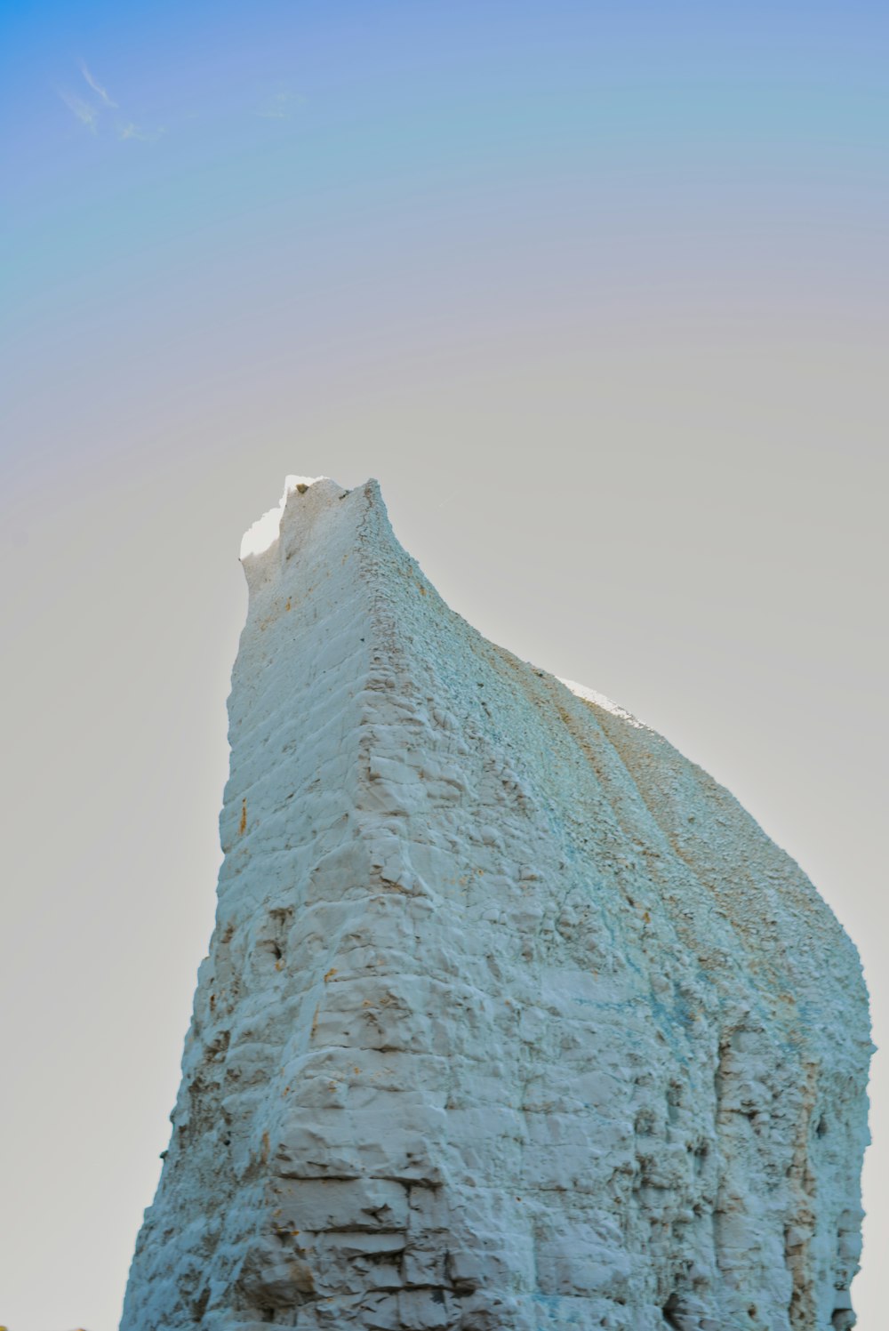 a very tall iceberg with a sky background