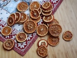 Close-up of glossy, thinly sliced dehydrated oranges arranged on a white marble surface.