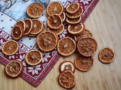 Close-up of glossy, thinly sliced dehydrated oranges arranged on a white marble surface.