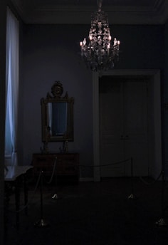 A moody, candle-lit room with chains and ropes arranged artistically on the walls.