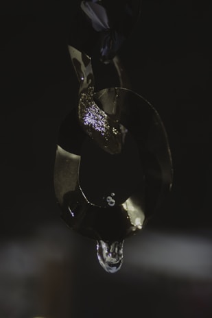 Artistic shot of a chrome chain necklace catching light on a dark background.