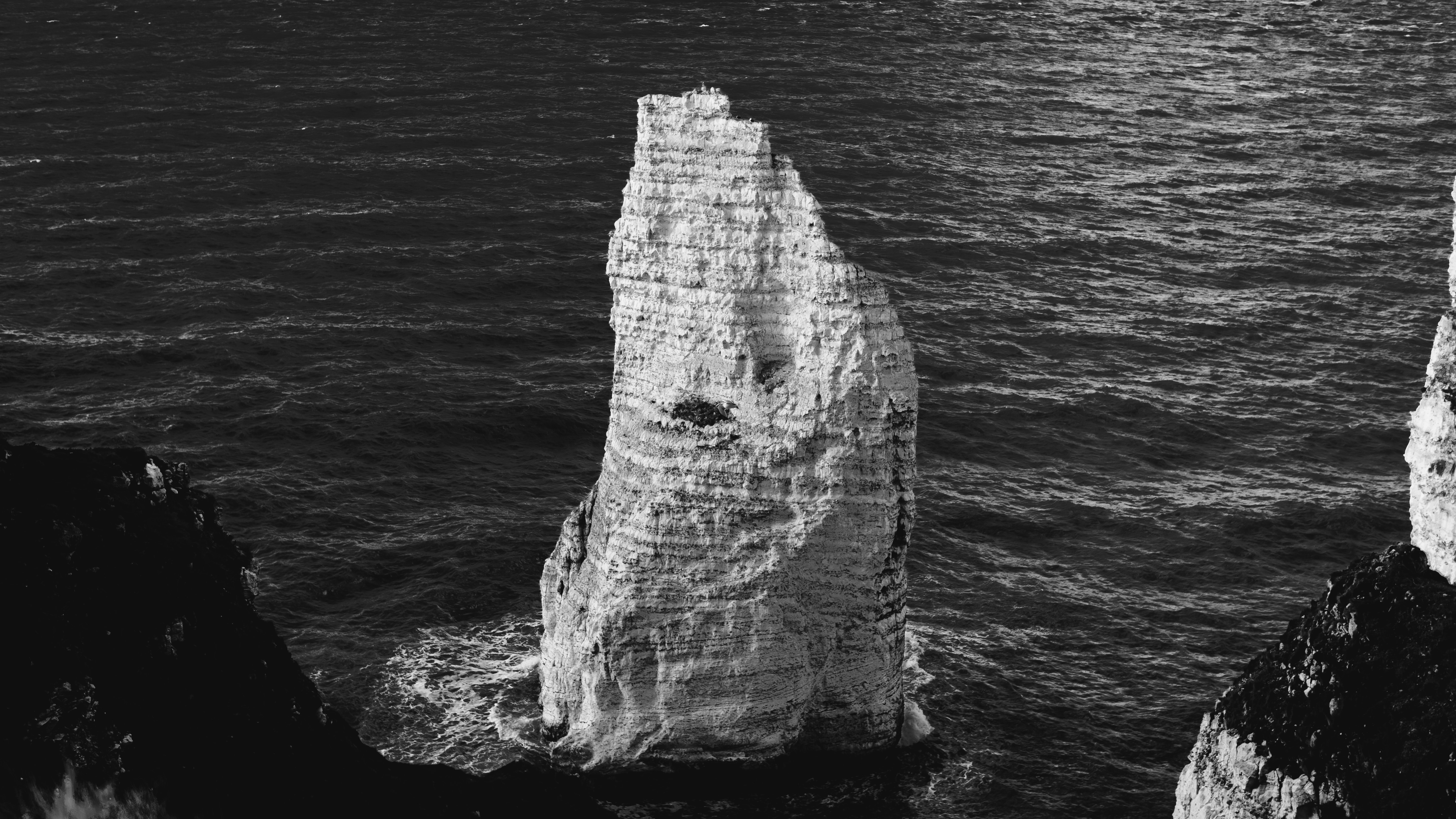 A large rock sticking out of the ocean photo Free Cliff Image on Unsplash