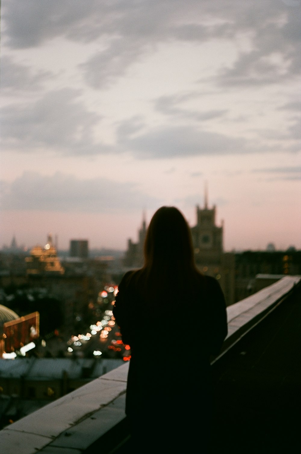 Una donna in piedi sulla cima di un tetto accanto a un edificio alto