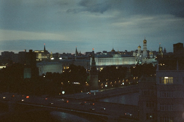 A bustling cityscape of Prague at dusk with illuminated historic buildings and bridges.