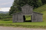An old wooden barn with a weathered roof in a serene landscape.