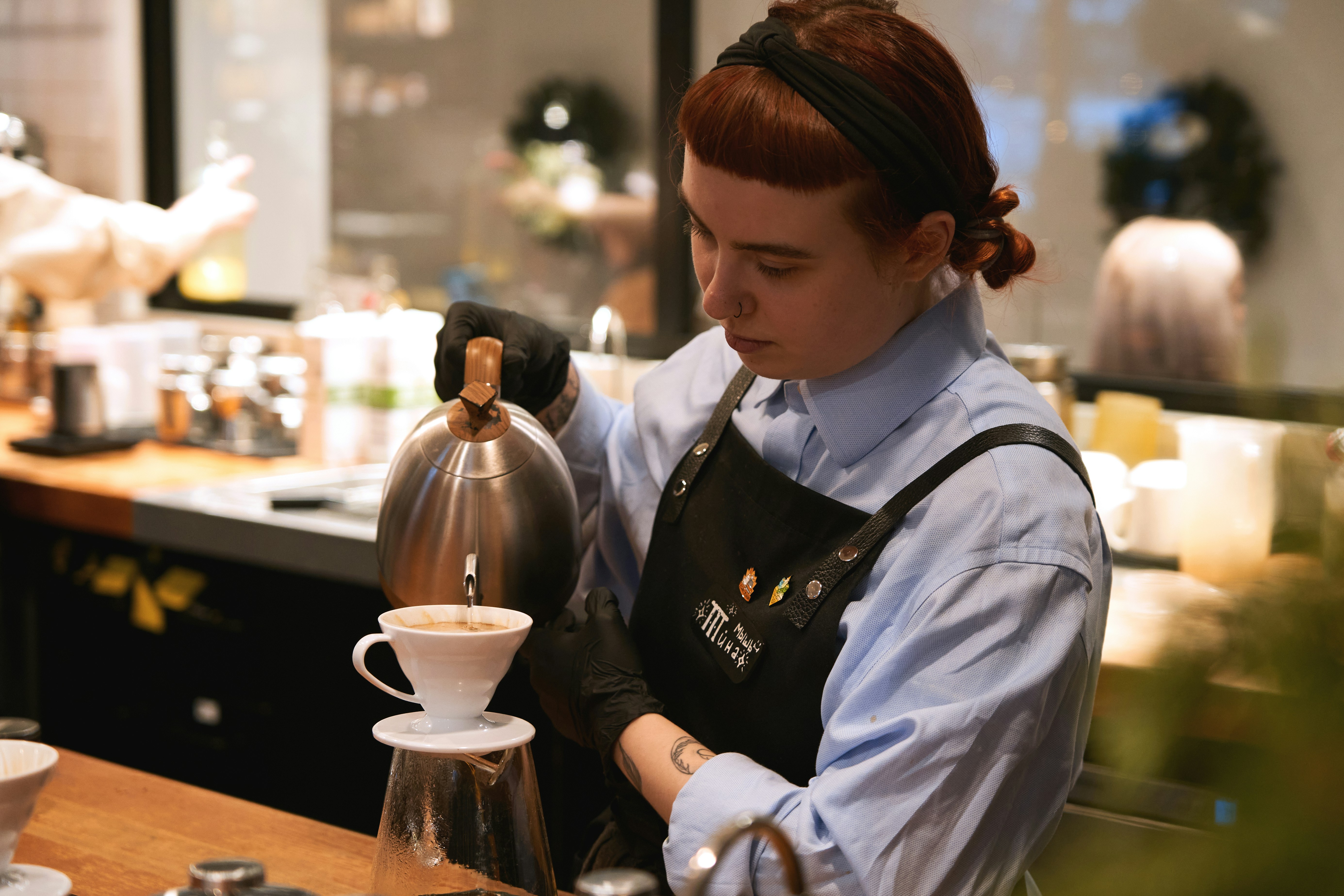 Barista in an apron pouring filter coffee