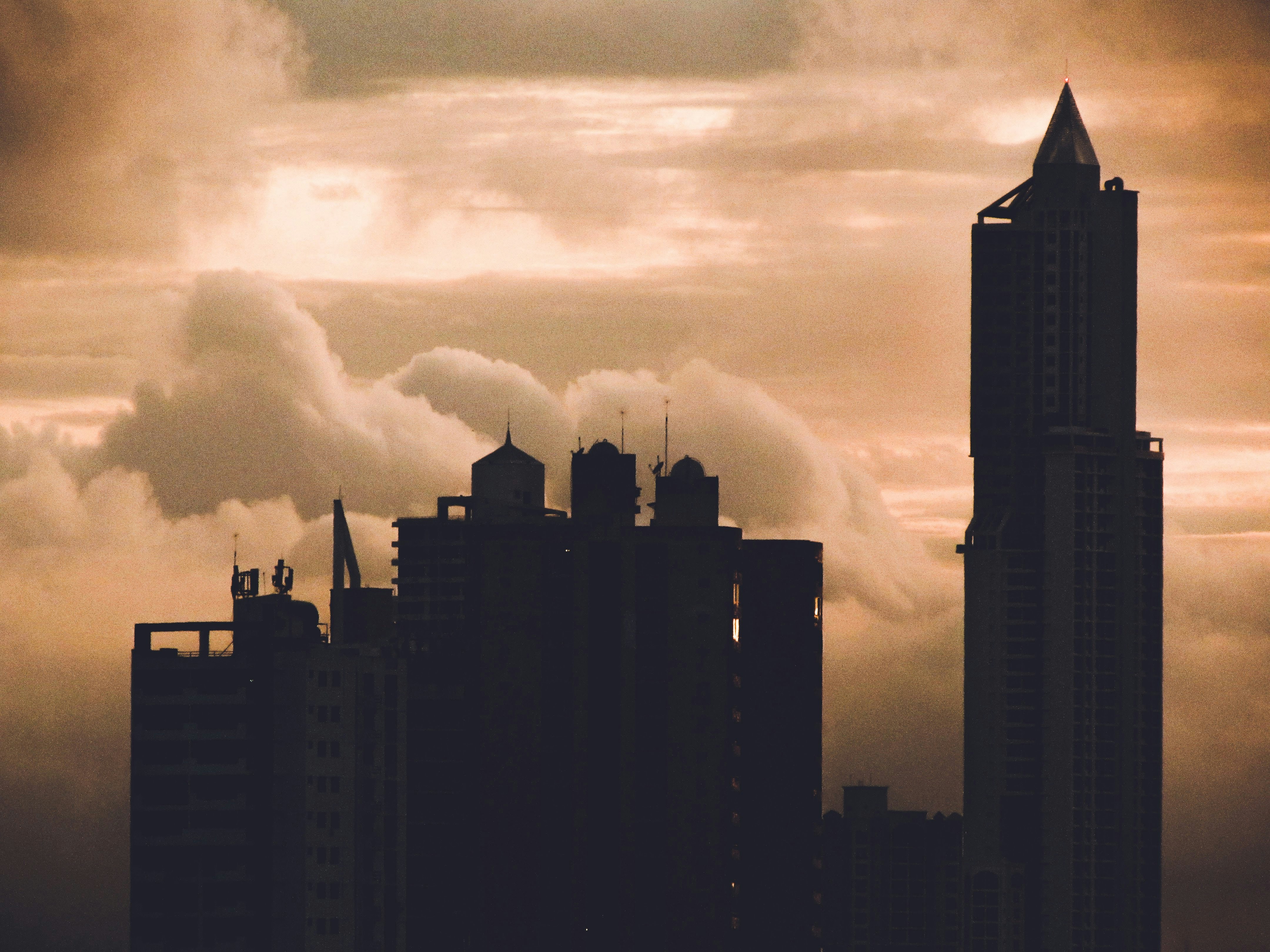 a city skyline with tall buildings and a cloudy sky