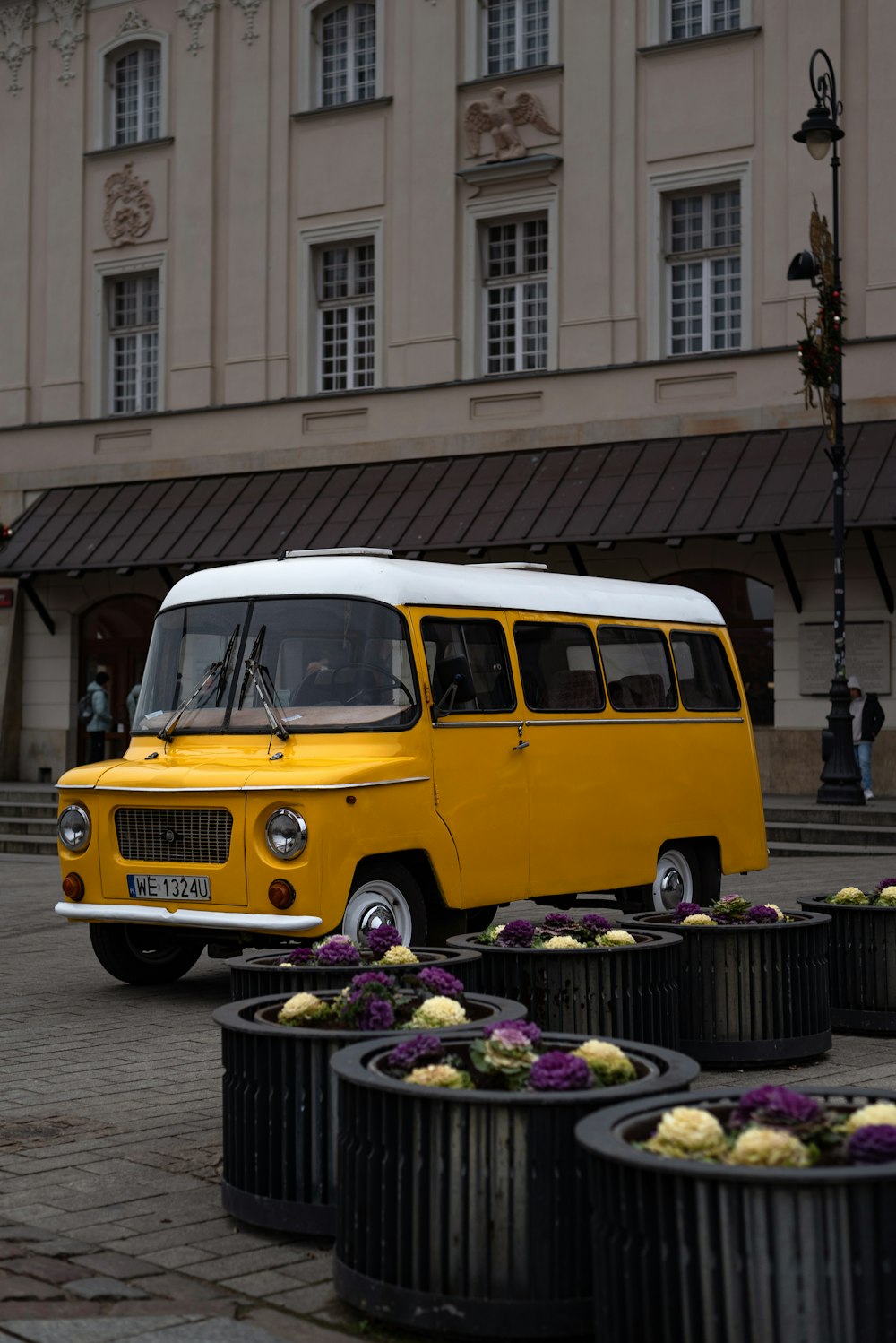 a yellow and white bus parked in front of a building