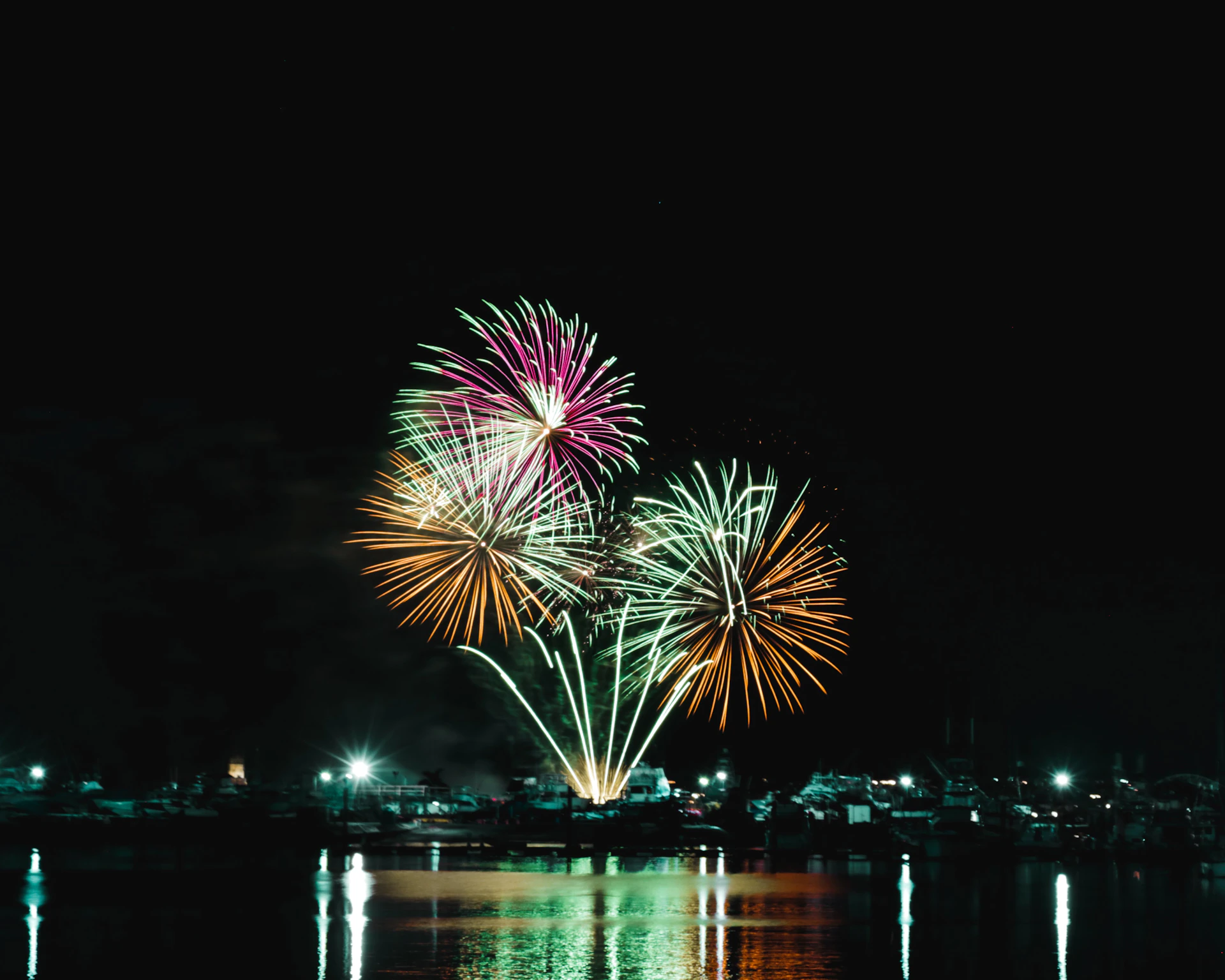 a fireworks display in the night sky over a body of water