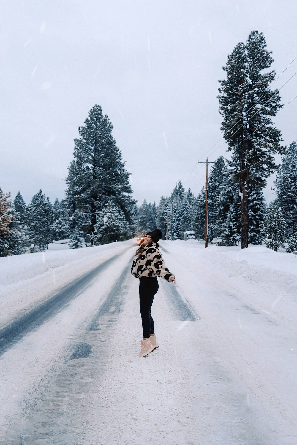 a woman walking down a snow covered road