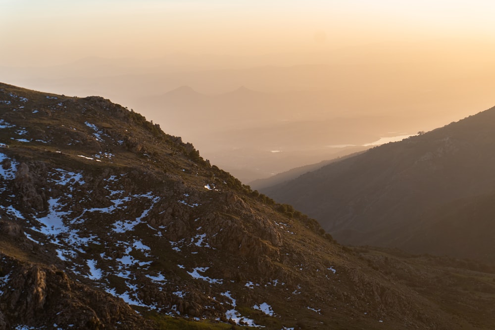 the sun is setting on a mountain side