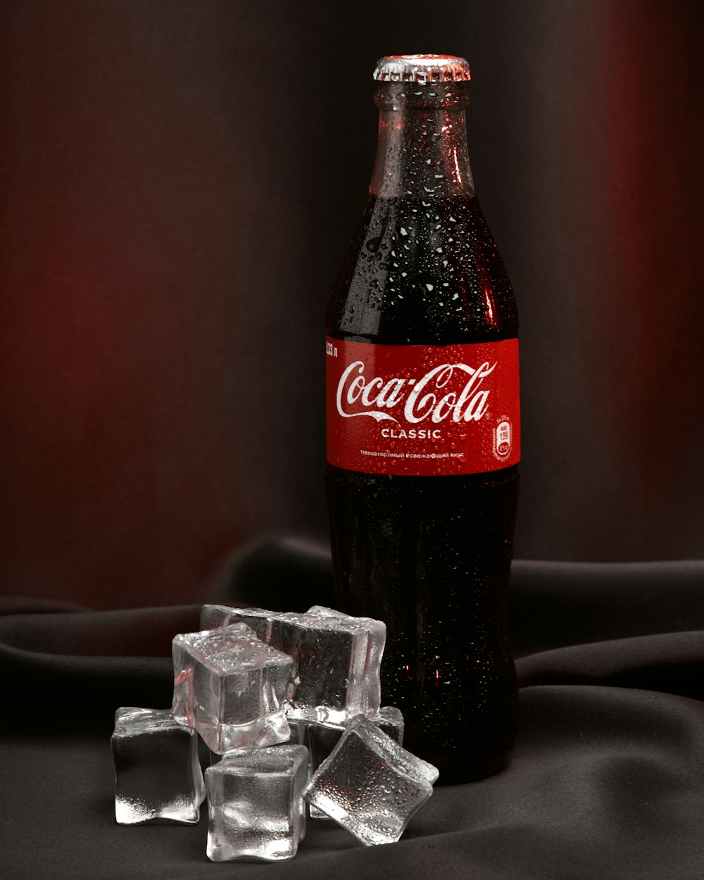 a bottle of coca cola sitting on top of ice cubes
