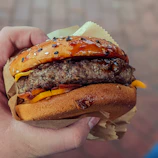 Close-up of a delicious gourmet burger being held by a happy customer.