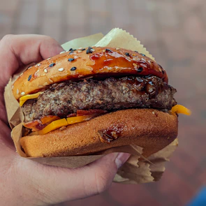 Close-up of a delicious gourmet burger being held by a happy customer.