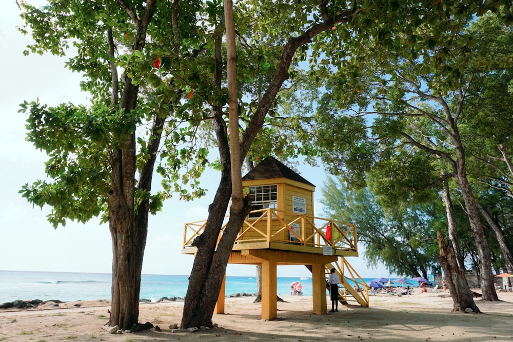 a lifeguard tower on a sandy beach next to trees