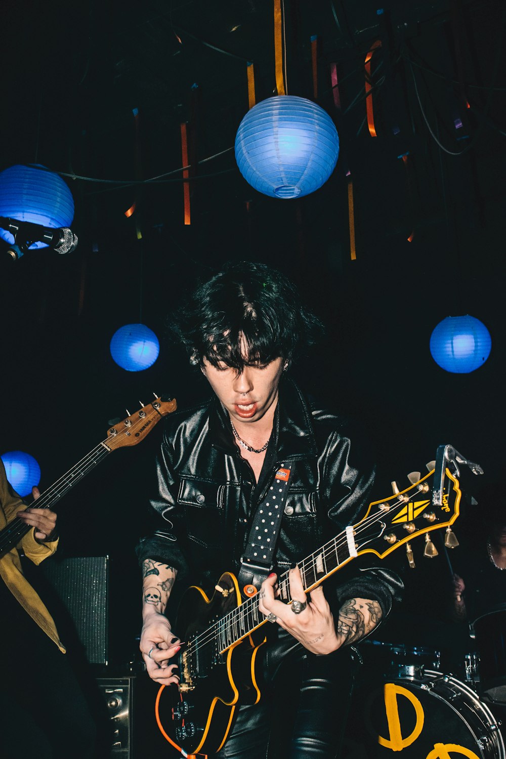 um homem com cabelo preto tocando uma guitarra