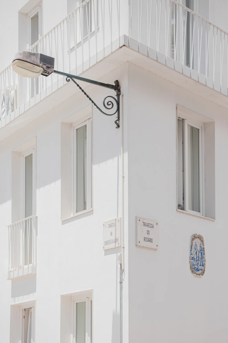 A white Lisbon facade with wrought-iron balconies and a street lamp