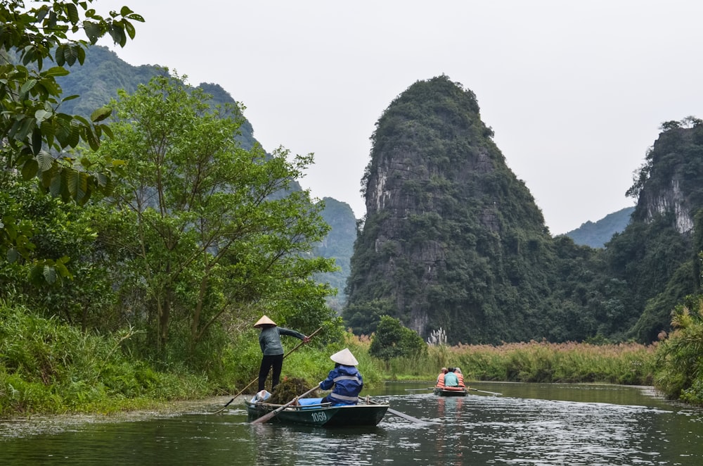 a group of people riding on the back of a boat down a river