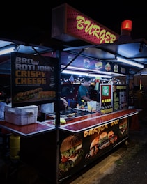 A vibrant street food stall with colorful tacos and burgers being served.