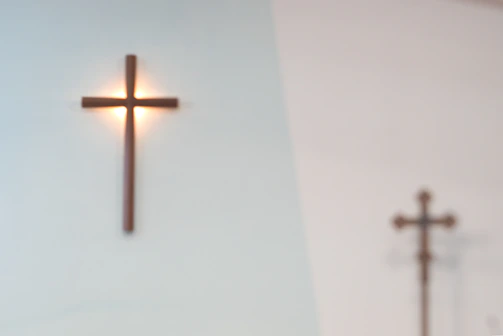 A close-up of a wooden cross with a soft glowing light behind it symbolizing hope.