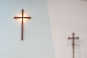 Orthodox cross hanging on aged wooden wall, casting a gentle shadow