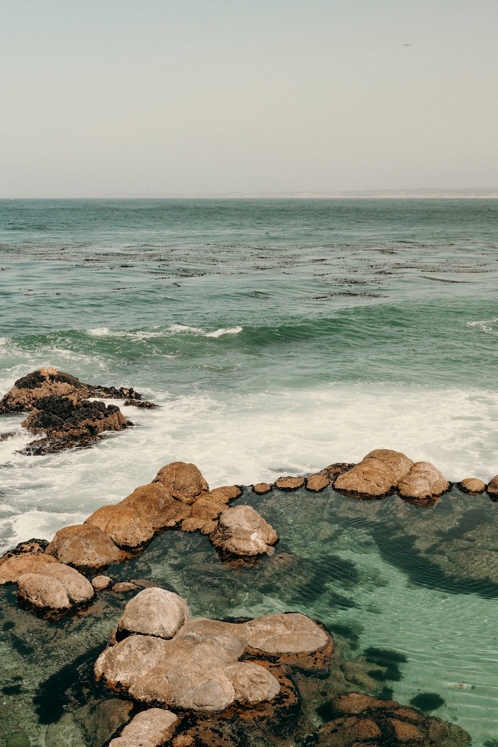 uma pessoa de pé em rochas perto do oceano