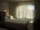 A softly lit bedroom featuring a curved footboard upholstered bed with plush bedding.