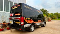 Professional driver greeting corporate clients beside a luxury minibus.