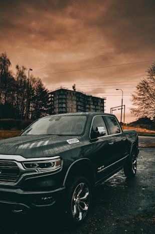 Jake's tow truck parked by a city street under a cloudy sky at dusk.