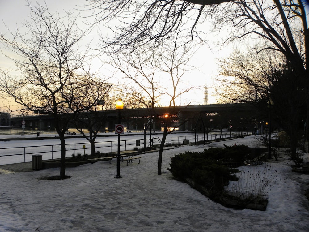 the sun is setting over a snowy park