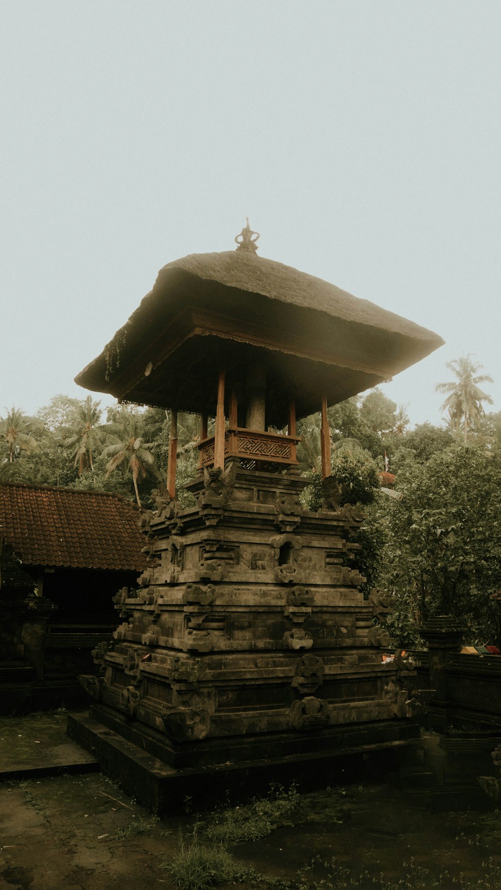 a stone structure with a wooden roof in the middle of a forest