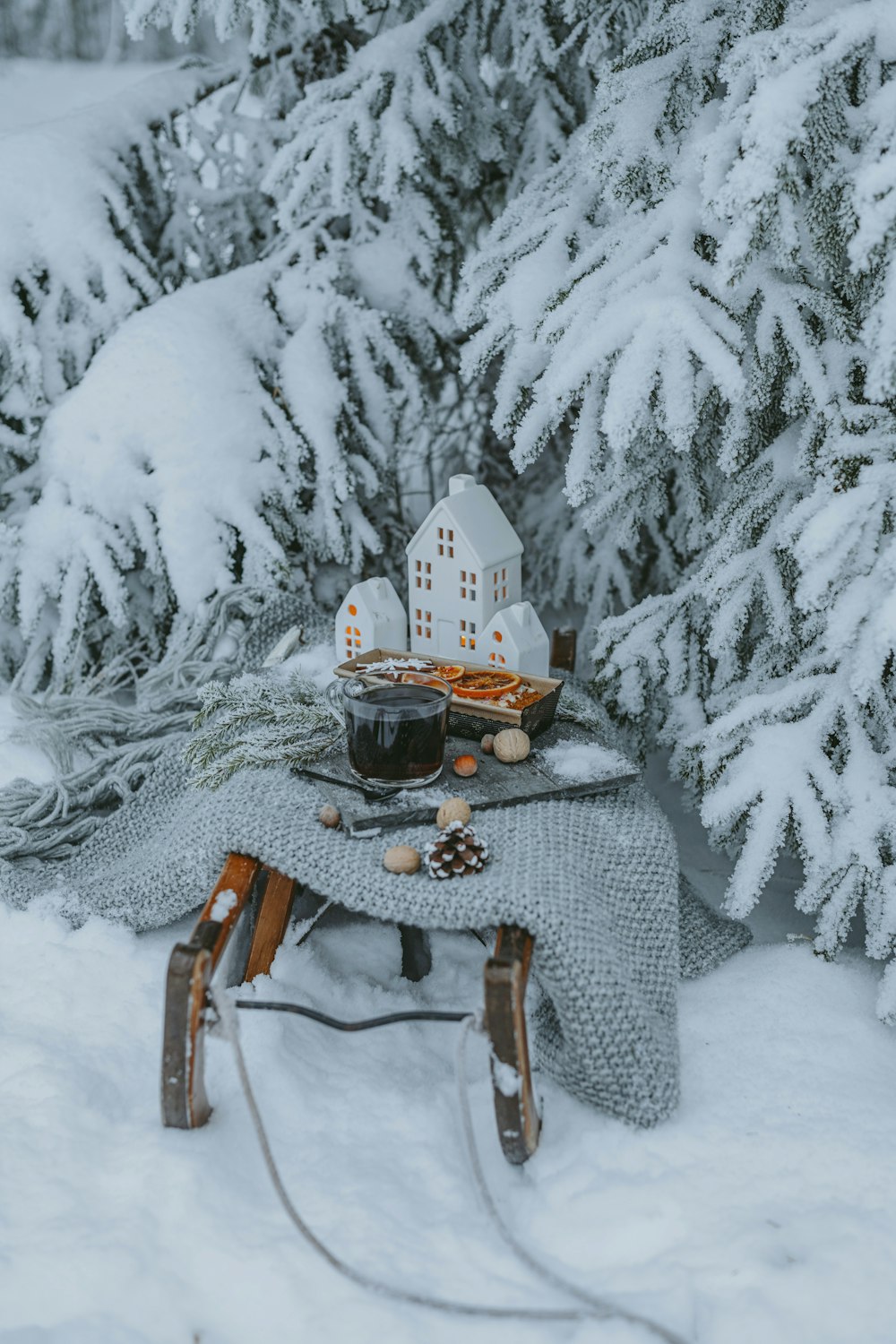 a sled with a blanket and a cup of coffee on it in the snow