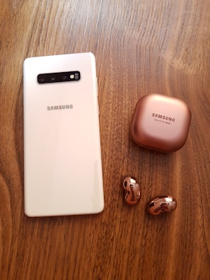 A smartphone placed next to wireless earbuds and a charging cable.