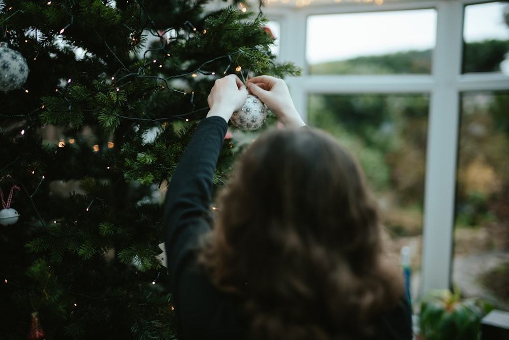 a woman is decorating a christmas tree