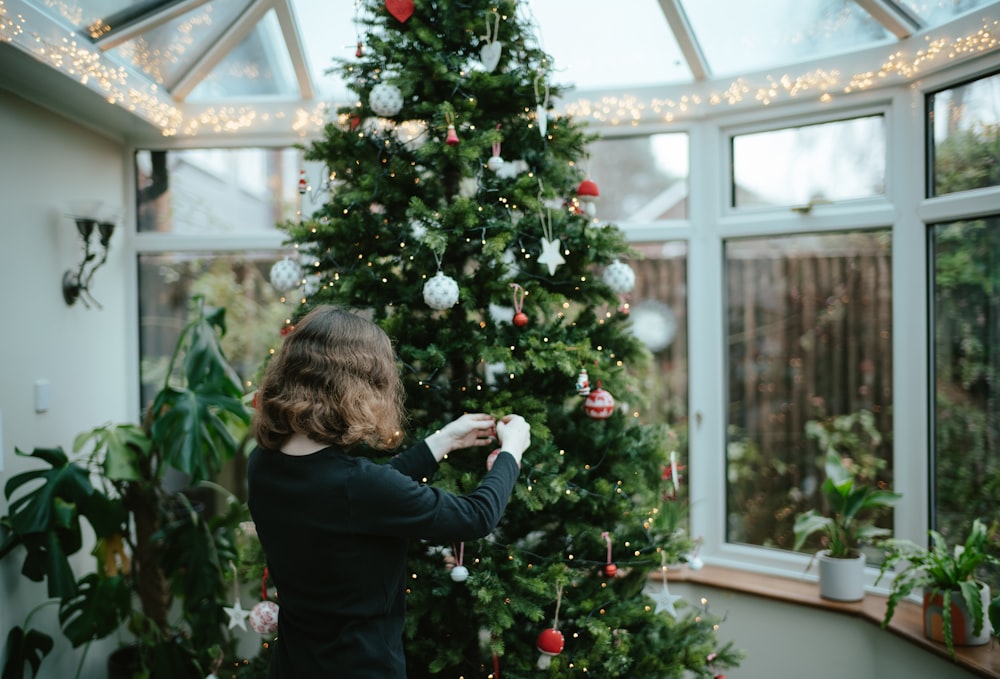 a woman decorating a christmas tree in a greenhouse