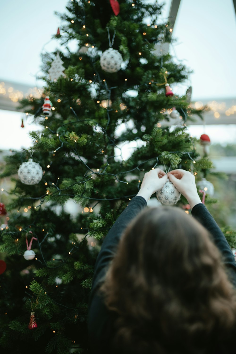 a woman decorating a christmas tree with ornaments