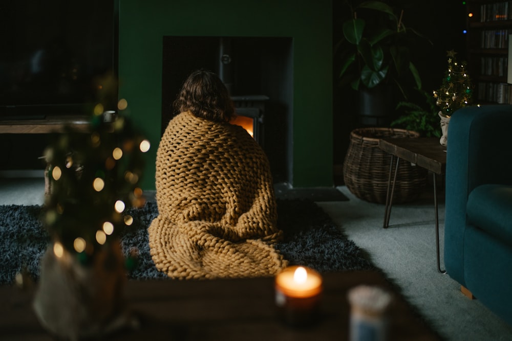 a woman wrapped in a blanket sitting on the floor